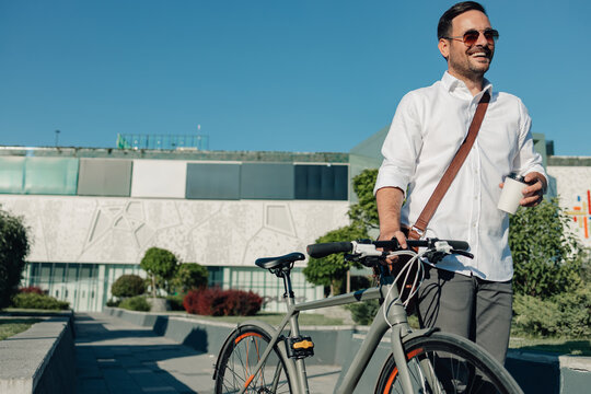 Businessman enjoying urban commute with bicycle and coffee