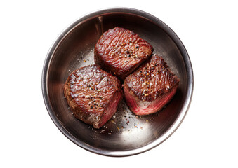 Round, seared steaks in metal bowl. Overhead view