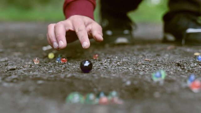 Detail of playing marbles outdoor on dusty way in slow motion
