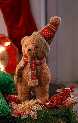 Christmas interior with vintage teddy bear figurine in a plaid Santa hat on the background of a red stocking for gifts and on a green blanket with gold stars as an interior decoration concept 