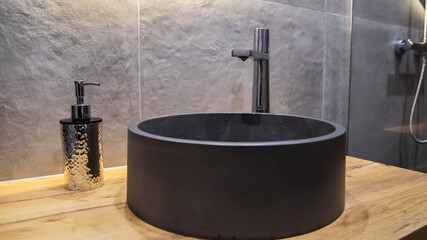 Stylish modern gray stone sink in the bathroom in a suspended wooden cabinet and a chrome tap. Gray...