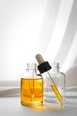 Glass dropper bottle with golden serum and shadow play