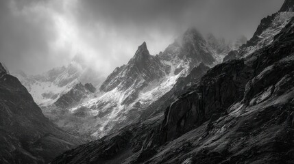 Obraz premium Dramatic monochrome landscape of snow-dusted mountain peaks under a cloudy sky
