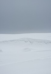 Obraz premium A vast, desolate landscape completely covered by deep white snowdrifts under a gray winter sky, illustrating the effects of harsh seasonal weather ,climate ,landscape ,natural