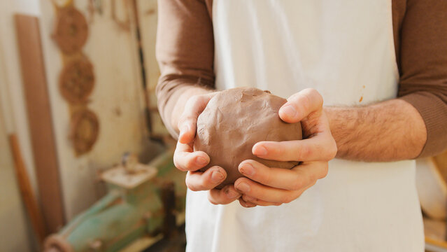Close Up Of Male Potter Holding Lump Of Clay In Ceramics Studio