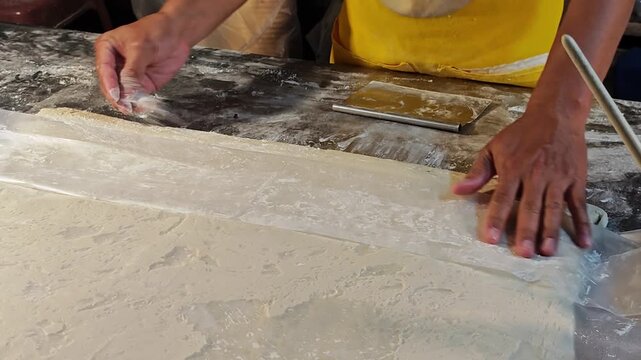 Sprinkles flour to raw dough stick.