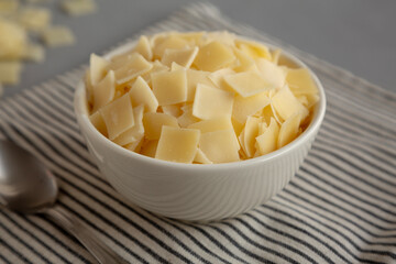 Hard Shaved Parmesan Cheese in a Bowl, side view. Close-up.