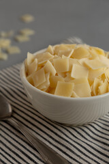 Hard Shaved Parmesan Cheese in a Bowl, side view. Close-up.