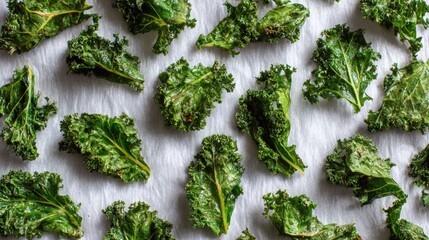 Crispy kale chips arranged on parchment paper ready for baking or freshly roasted, healthy vegetable snack alternative with vibrant green leaves and natural texture
