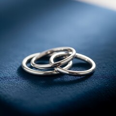 Elegant Silver Rings Intertwined on a Deep Blue Surface.
