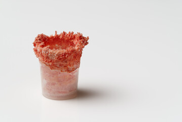 Crystallized red reagent in a plastic cup. Mock-up on a white background.