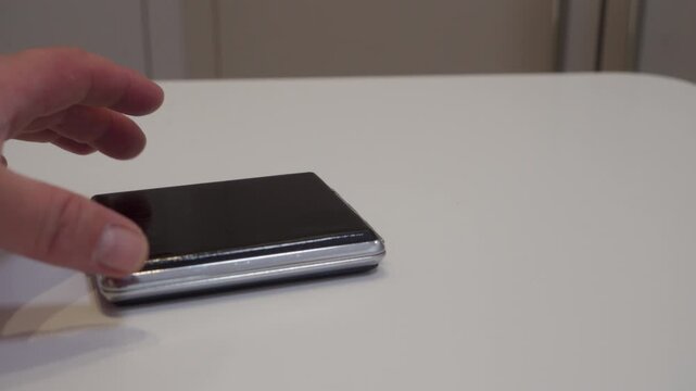 A metal and glossy plastic compact mirror is pushed across a smooth, hard table surface. The base drags lightly on the surface, producing a gentle scrape.