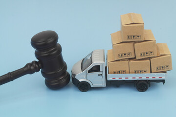Judge gavel and lorry truck with many boxes on blue background.	