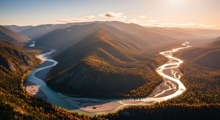 Aerial view of a winding river through an autumn mountain valley at sunset.