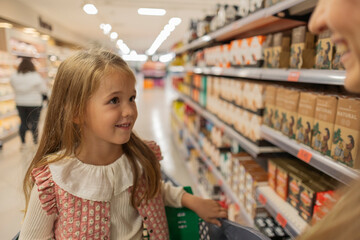 Little girl smiling while shopping in a supermarket aisle