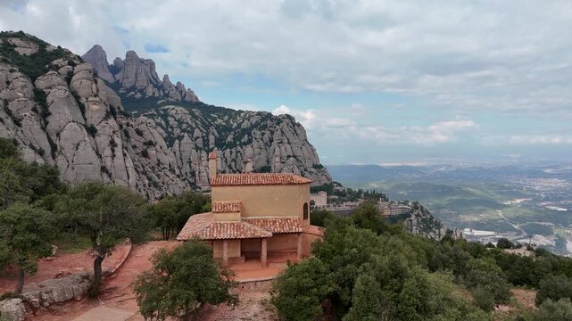 Aerial pass revealing mountain monastery behind ancient chapel