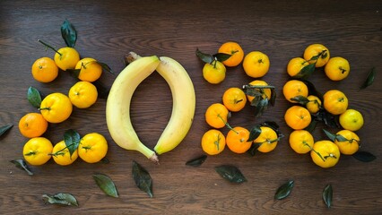 2026 made of tangerines and bananas on a wooden background