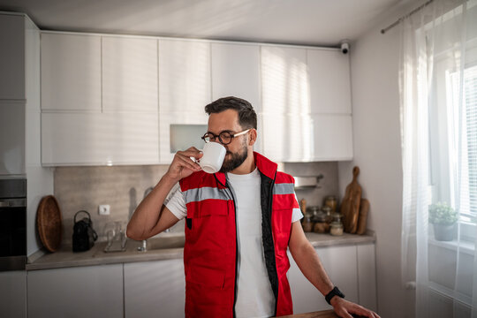 Paramedic man drinking coffee during break in kitchen