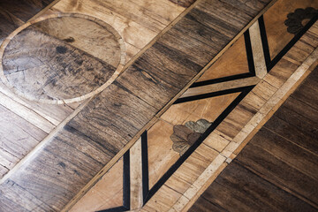 Aged wooden parquet floor featuring a circular inlay and a bold diagonal geometric band