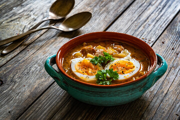 Potato sausage soup with boiled egg on wooden table	