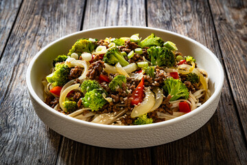 Ground beef and broccoli noodles on wooden table