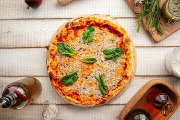 Freshly baked Italian pizza with tomato sauce, spinach leaves, and melted cheese on a wooden board