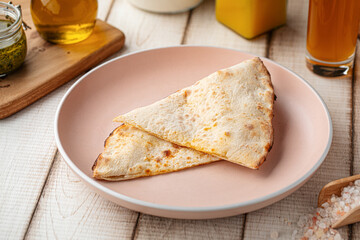 Fresh warm flatbread served folded on a rustic plate with soft natural tabletop background