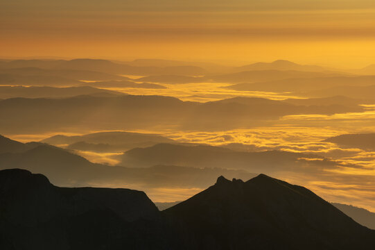 Aerial view of the Jahnaci stit peak shrouded in the golden hues of dawn, a serene landscape of mountains piercing through the ethereal mist, Vysoke Tatry, Presov Region, Slovakia.