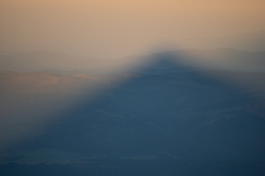 Aerial view of the imposing shadow of Jahnaci stit peak stretches across the serene landscape, bathed in the warm hues of twilight, Vysoke Tatry, Presov Region, Slovakia.