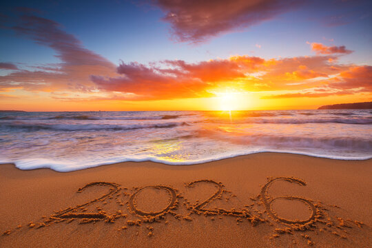 Fototapeta Happy New Year 2026 concept, lettering on the beach. Written text on the sea beach at sunrise.