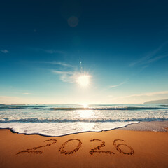 Beautiful cloudscape over the sea horizon at sunrise. appy New Year 2026 text written on seashore.