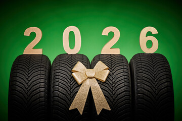 Car tires, new tyres, winter wheels isolated on green background with bow ribbon present 2026 new year celebration