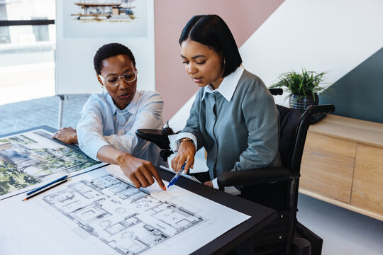 Two women reviewing building blueprints together in a modern office environment