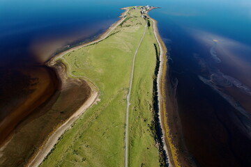 Aerial view of a ribbon of vibrant green meadow bisecting the dark, swirling waters that meet at a distant point, Dornoch, United Kingdom.
