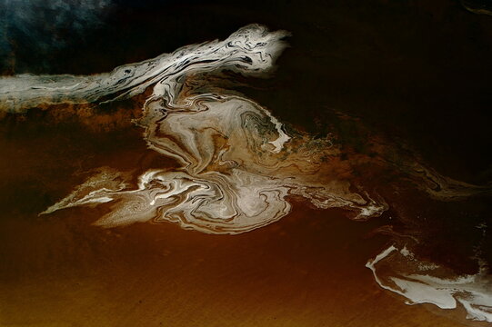 Aerial view of marbled patterns swirling across the water's surface, a dance of light and shadow creating an abstract masterpiece, Dornoch, United Kingdom.