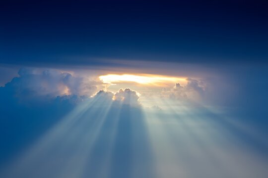 Sun rays shining through clouds creating a heavenly scene with a blue sky above it all