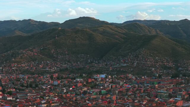 Cusco city Plaza De Armas street cityscape buildings Peru aerial drone late vive en el cusco mountain hillside Cuzco Saqsaywaman Anta province afternoon sunset rainy season clouds blue sky backwards