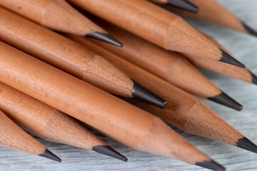 wooden pencils with black lead on corrugated paper, several monochrome pencils for sketches or graphic work are in a row.