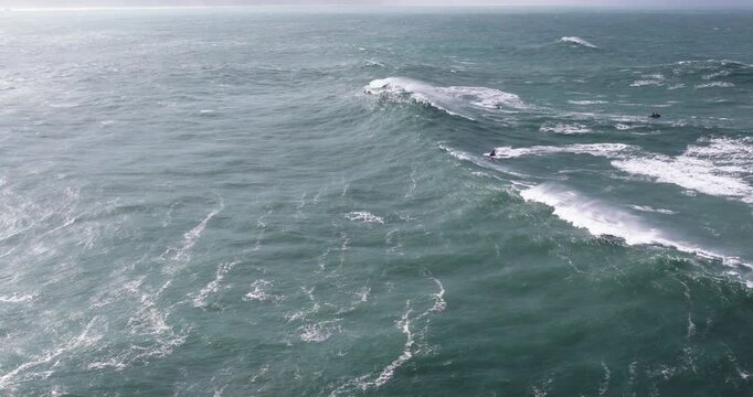 Aerial drone shot of big wave surfer surfing a wave on a day with giant waves in Nazare, Portugal, Europe. Nazaré, big wave surfing town with biggest waves in the world. Shot in ProRes 422 HQ