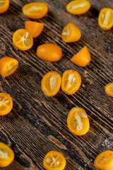 lots of ripe orange kumquat cut in half on a wooden table, a group of sliced kumquat fruits on a wooden table and board