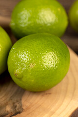 ripe citrus limes scattered on a wooden table in the kitchen, ripe and juicy lime fruits for cooking both sauces and drinks and other food