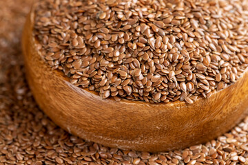 flax seeds poured into a wooden bowl, a round wooden bowl filled with flax seeds, which can be used...