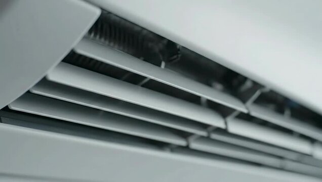 Close up of an air conditioner vent against a white ceiling