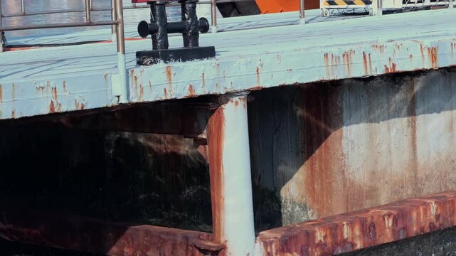 A seaport. Water laps against the metal port structures. The pier and loading equipment, cranes in the background. Transport industry. Machines and machinery