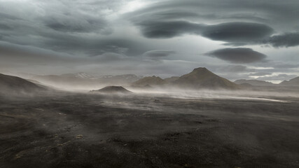 Aerial view of a desolate landscape where the dark earth meets the brooding sky, a symphony of gray and brown punctuated by distant peaks, Landmannalaugar, Rangarbing ytra, Iceland.