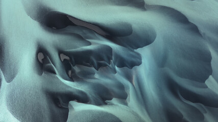 Aerial view of glacial rivers carve through the stark, contrasting landscape of Landmannalaugar, Iceland, creating surreal patterns of turquoise and shadow, Landmannalaugar, Rangarbing ytra, Iceland.