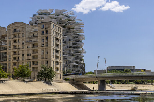 View of striking architecture contrasts old and new, with a modern white building rising behind a classic stone structure, Montpellier, Occitanie, France.