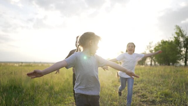 Children running in grassy field child and kid laugh while they play under warm sunlight in open grass field with friend and family nearby dog in distance natural energy and joyful movement.