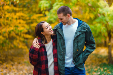 Fototapeta premium Happy interracial couple walking and holding hands in autumn forest.