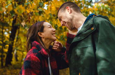 Fototapeta premium Smiling man and woman sharing a romantic intimate moment in an autumn park.